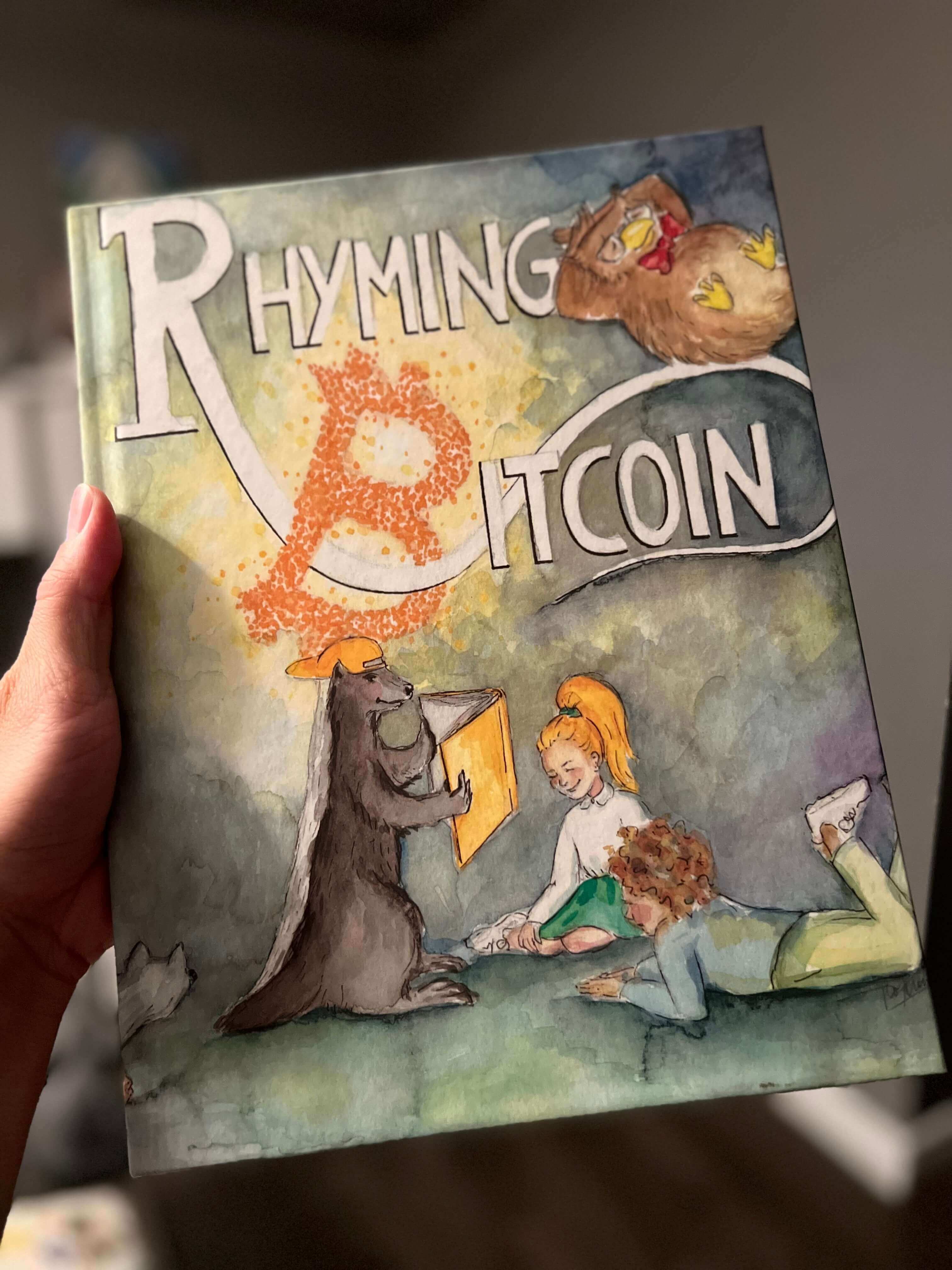 Holding a copy of the children's book Rhyming Bitcoin.