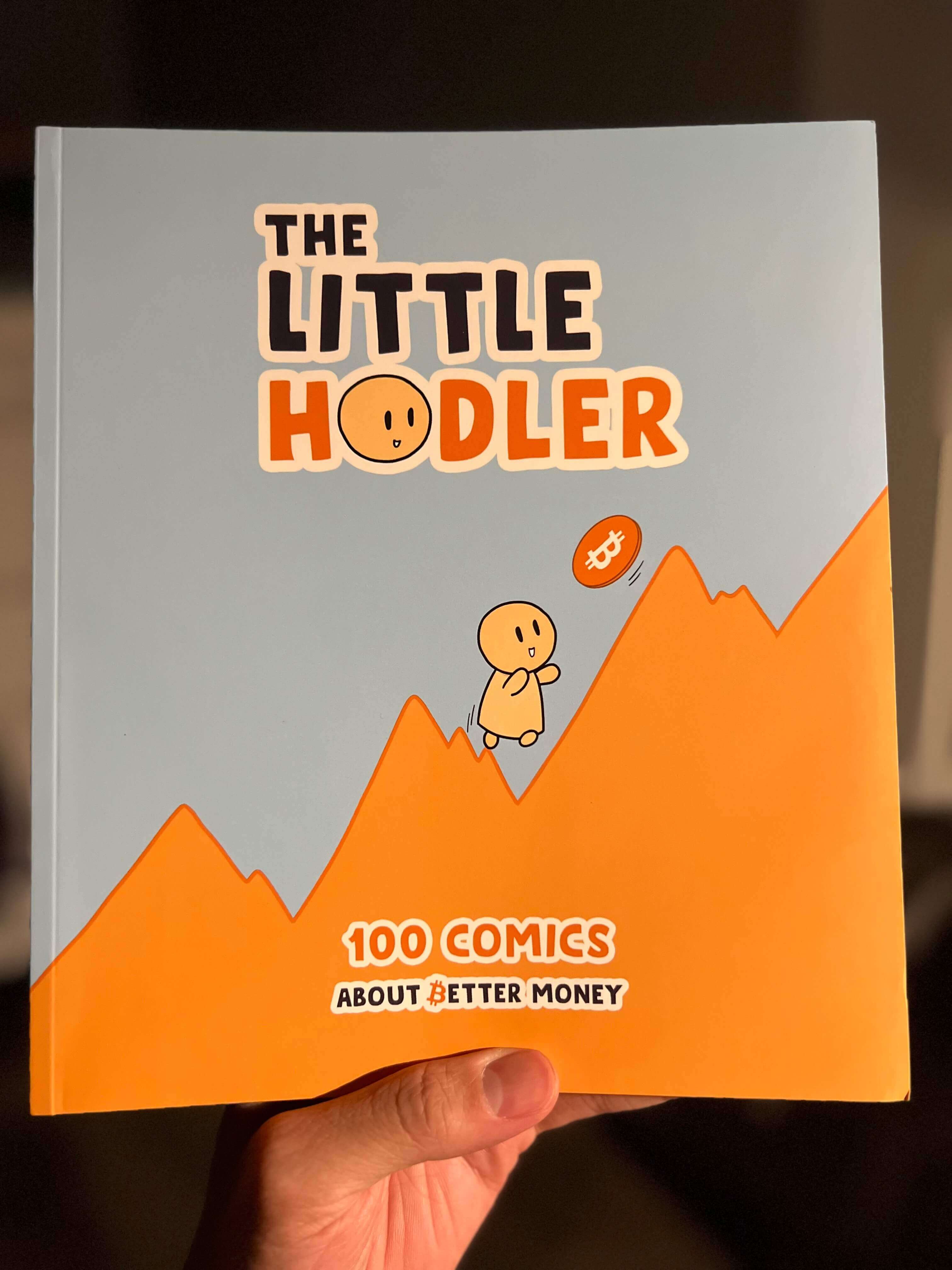 Holding a copy of the book The Little Hodler: 100 Comics About Better Money.